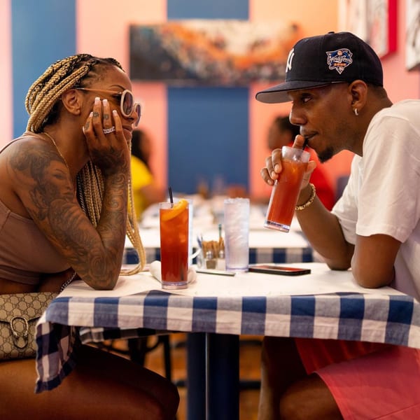 Two people enjoying brunch at The Breakfast Boys, with drinks on a blue and white checkered table.