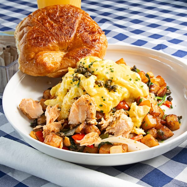 The Breakfast Boys' salmon scramble with potatoes, peppers, and onions, served with a croissant.