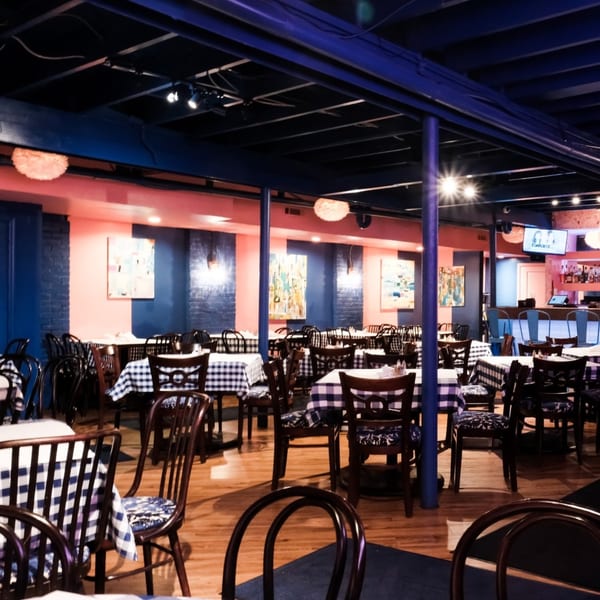 The Breakfast Boys dining room with blue and pink walls, checkered tablecloths, and a bar area.
