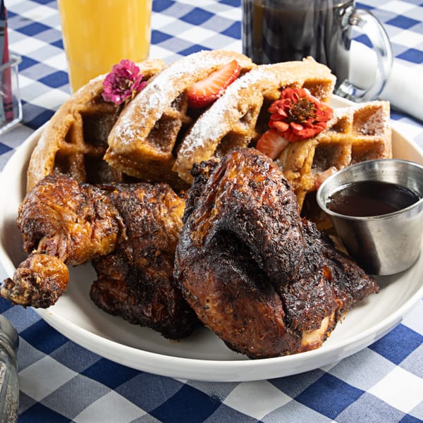 The Breakfast Boys' chicken and waffles with syrup, powdered sugar, strawberries, and edible flowers.